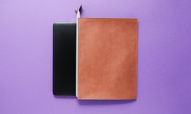 Dunkler Laptop schaut aus Lederlaptoptasche hervor Dunkler Laptop schaut aus Lederlaptoptasche hervor